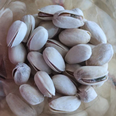Une poignée de pistaches salées dans un bol transparent, vue de dessus